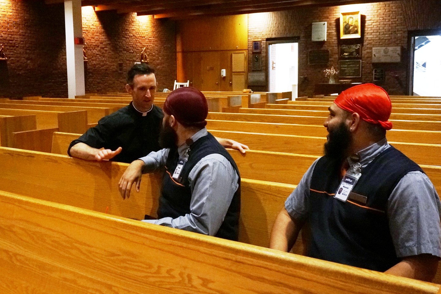 The Rev. Brian Daley speaks with two airline employees after they prayed at Our Lady of the Airways, a Catholic chapel at Logan International Airport, in Boston on Friday, Aug. 29, 2025.