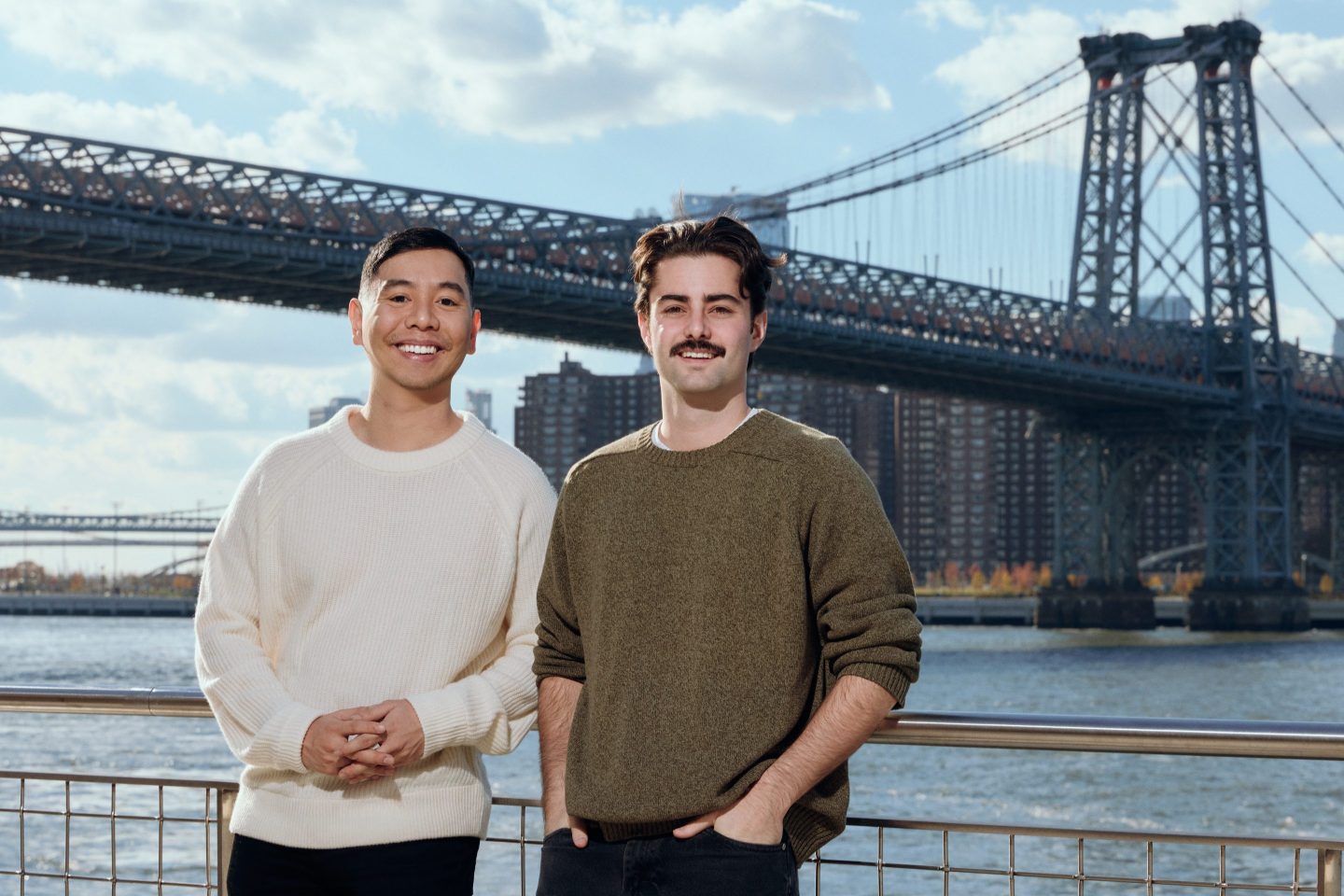 Two men stand in front of the Manhattan Bridge