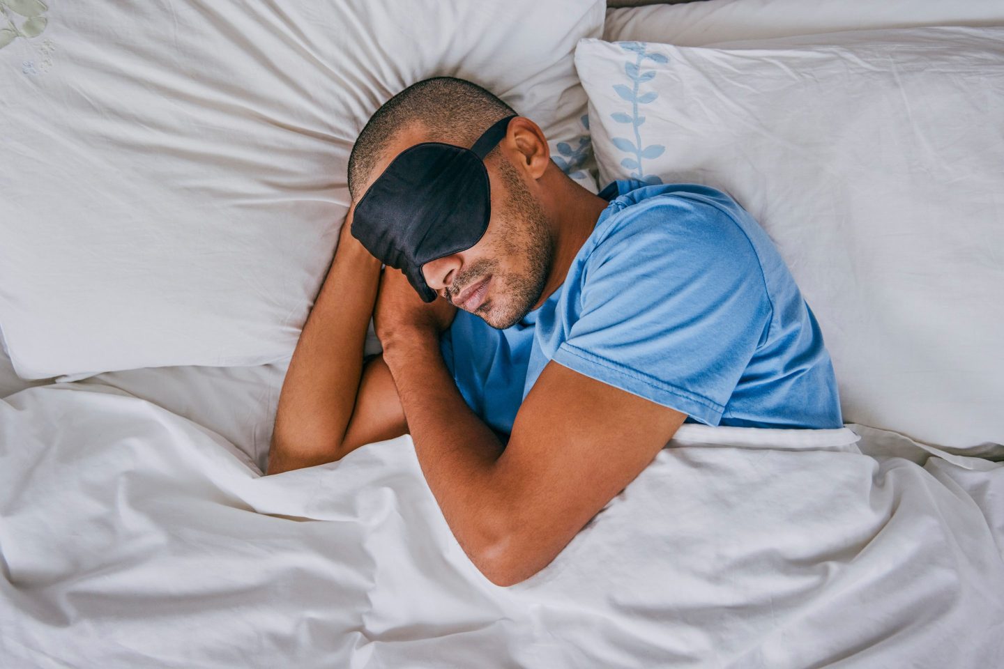 Man sleeping in bed wearing eye mask