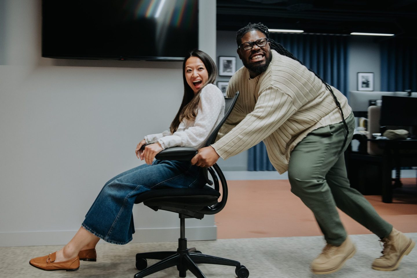 A man pushing a woman in a chair in an office, having late night antics