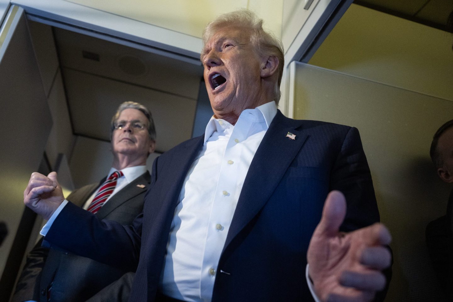 Trump addresses the press corps while motioning to Scott Bessent