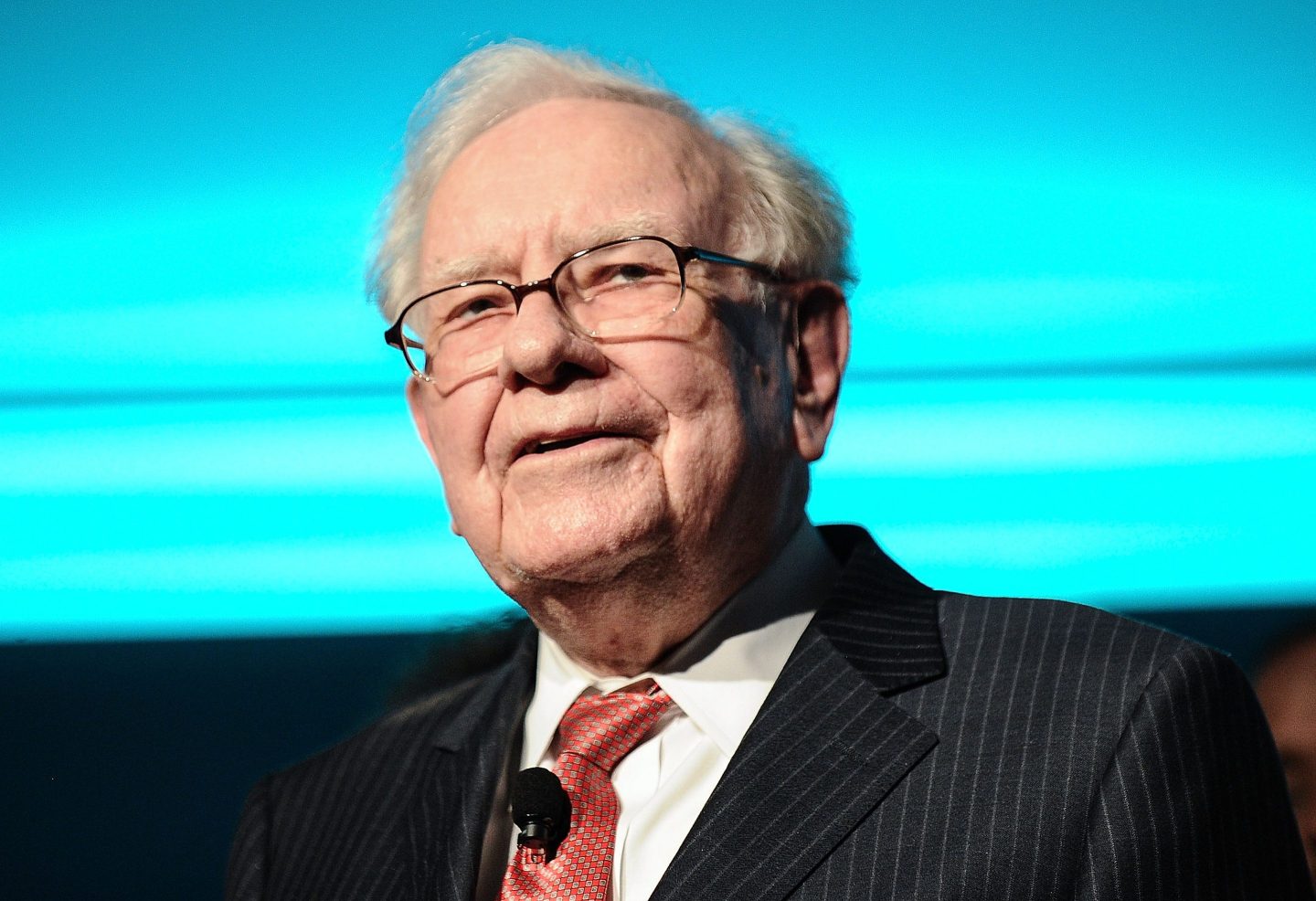 Warren Buffett in front of a sky blue background